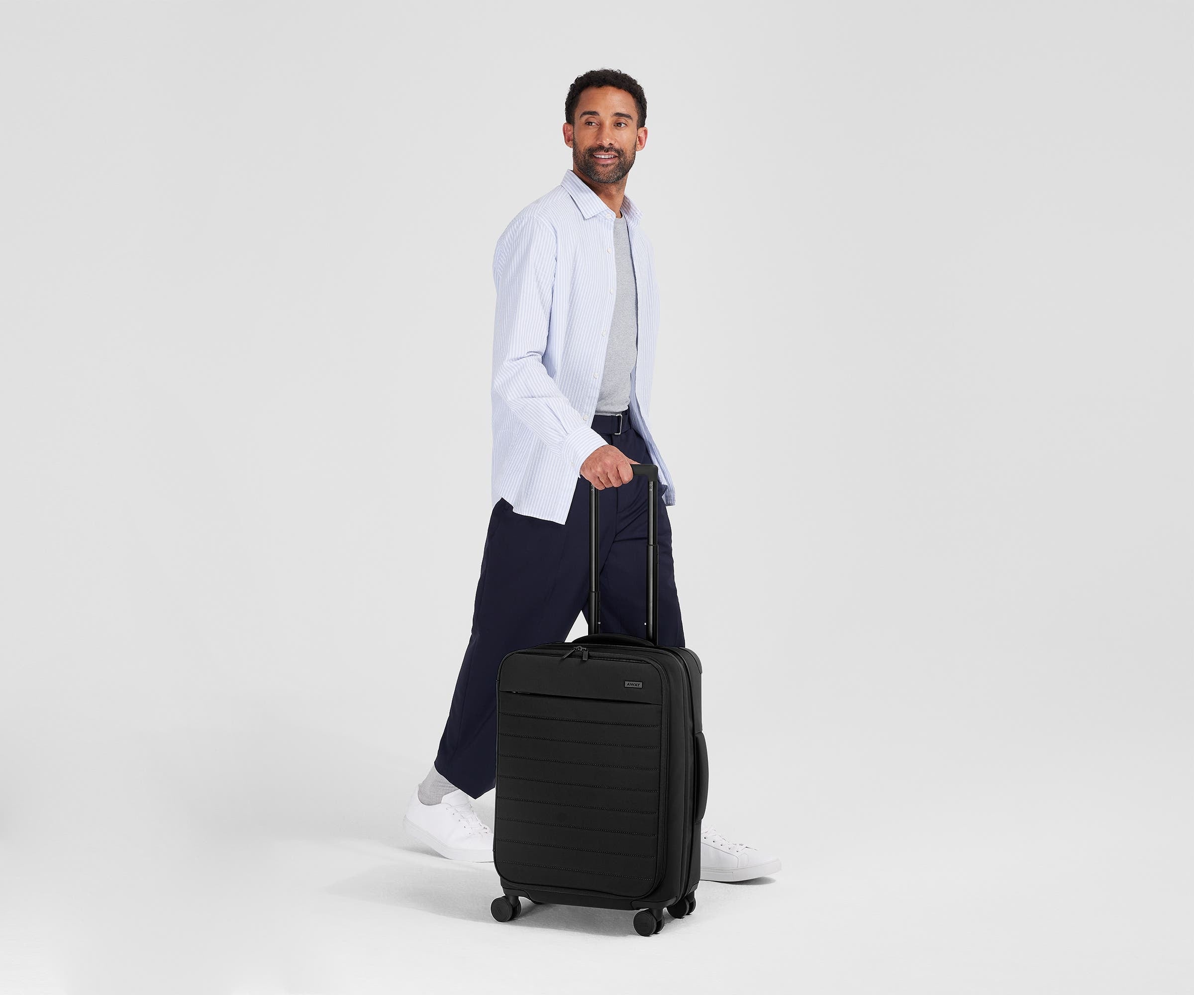 Person standing next to the Softside Bigger Carry-on for scale