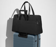 Weekender sitting on an Away Large suitcase, using the trolley sleeve pass-through