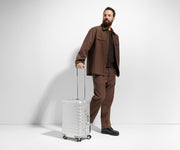 Person standing next to an Aluminum Bigger Carry-On suitcase in Silver