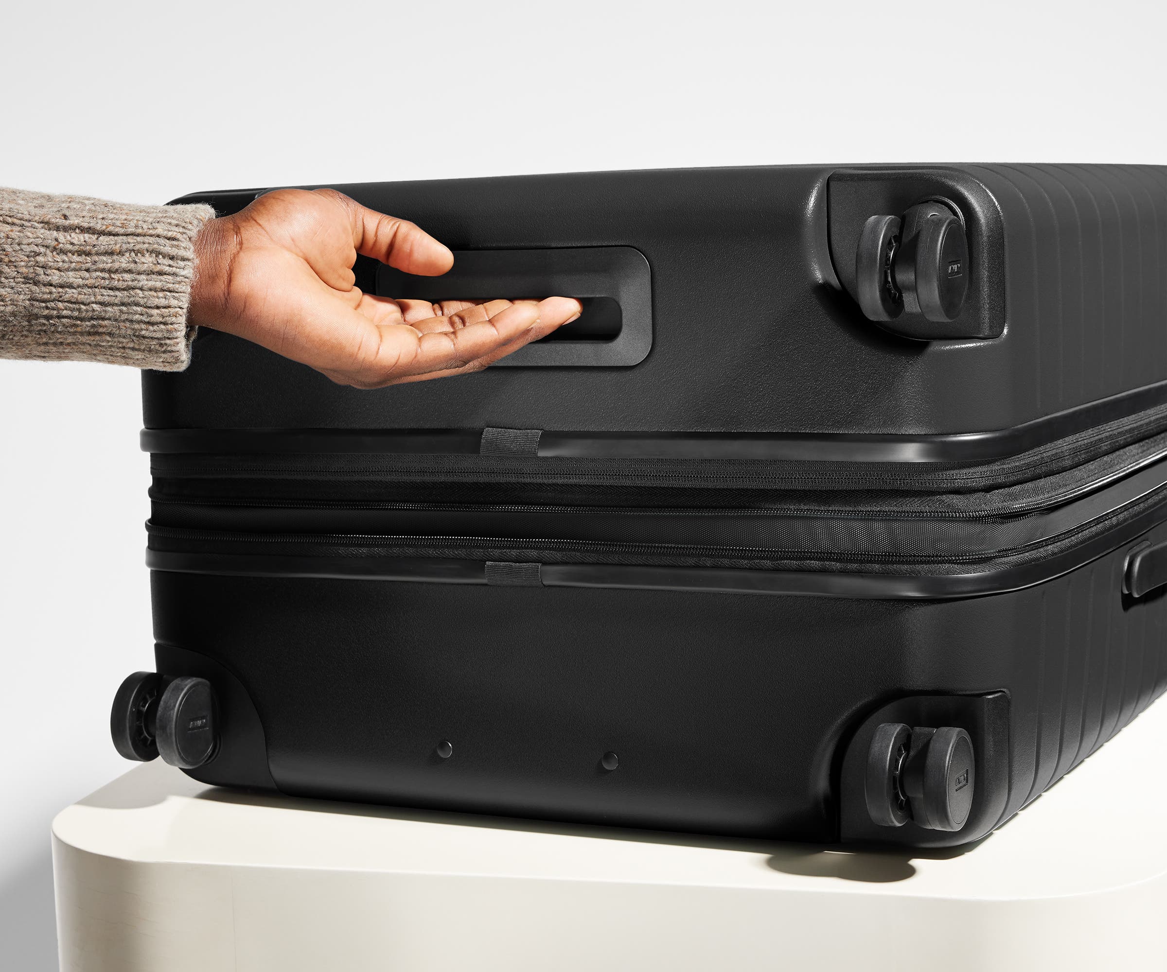 The Medium Flex suitcase in Jet Black shown from below highlighting the underside grab handle