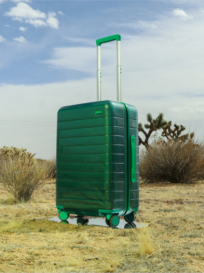 The limited edition Bigger Carry-On in Translucent Green from the Translucent Collection pictured in Joshua Tree National Park against a desert background.