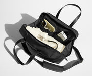 Main compartment packed with a sweater, notebook, and sunglasses. A key is attached to the interior key leash.