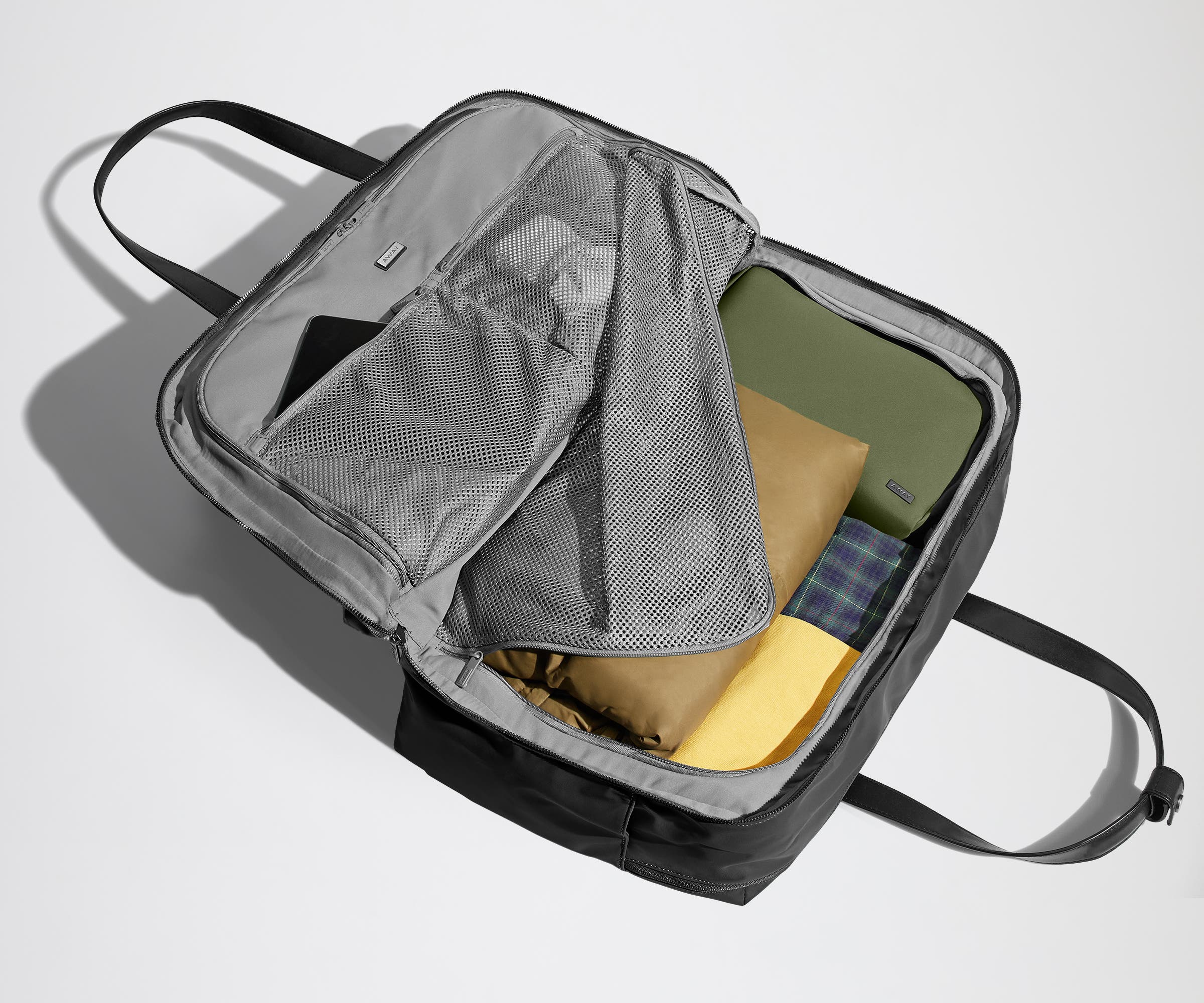 Open clamshell Weekender bag packed with travel essentials, including clothes and Small Toiletry Bag